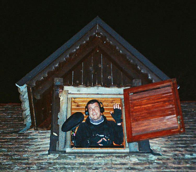 Daniel looking througha a window of a old wooden house.