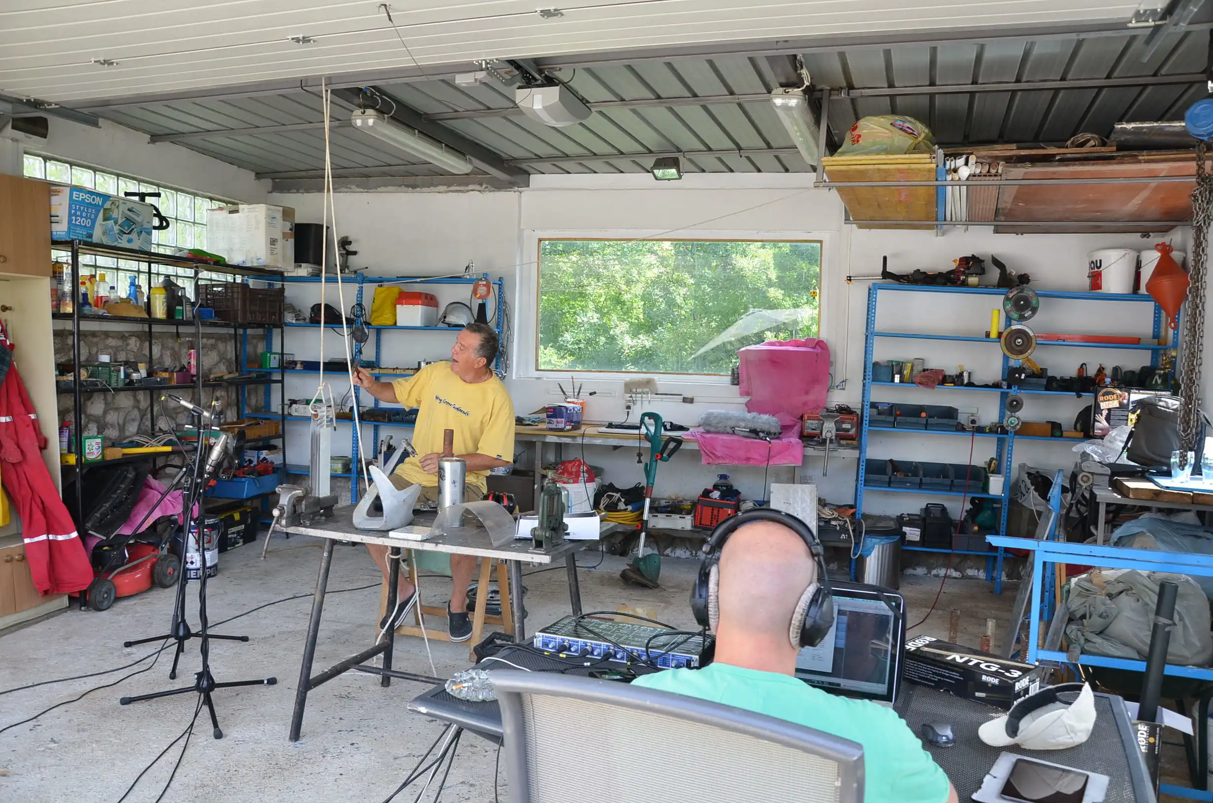 Working garage with Matko sitting at the computer a branko sitting near the recording tools.