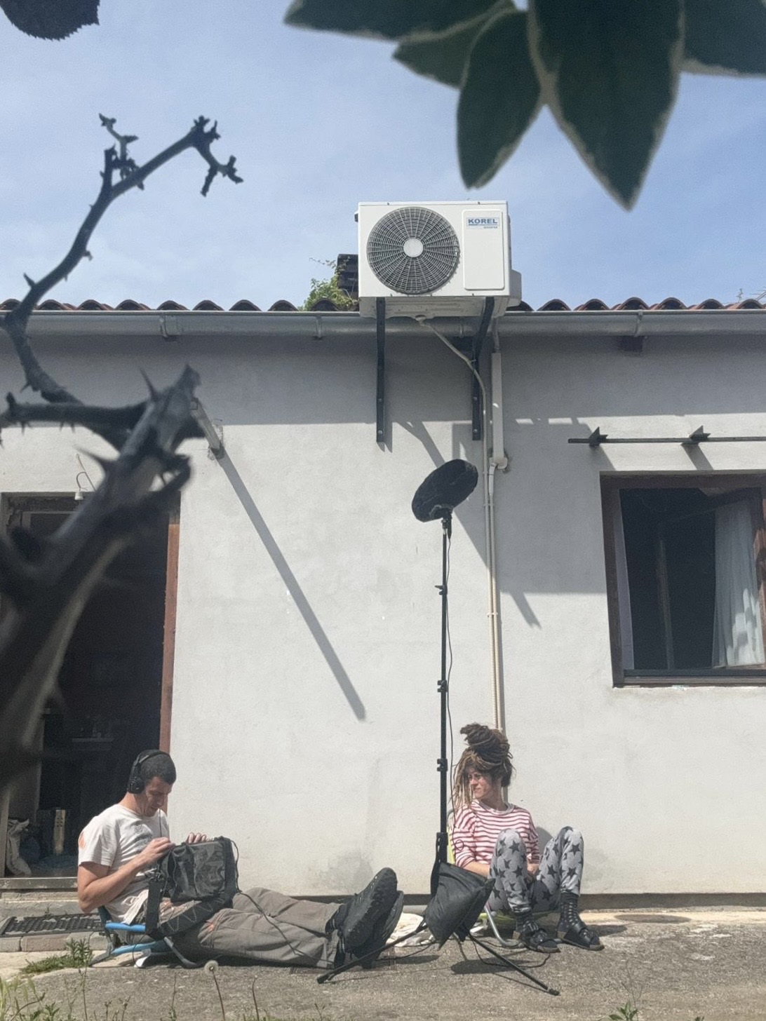 Petra and Daniel sitting in front of their house and recording audio.